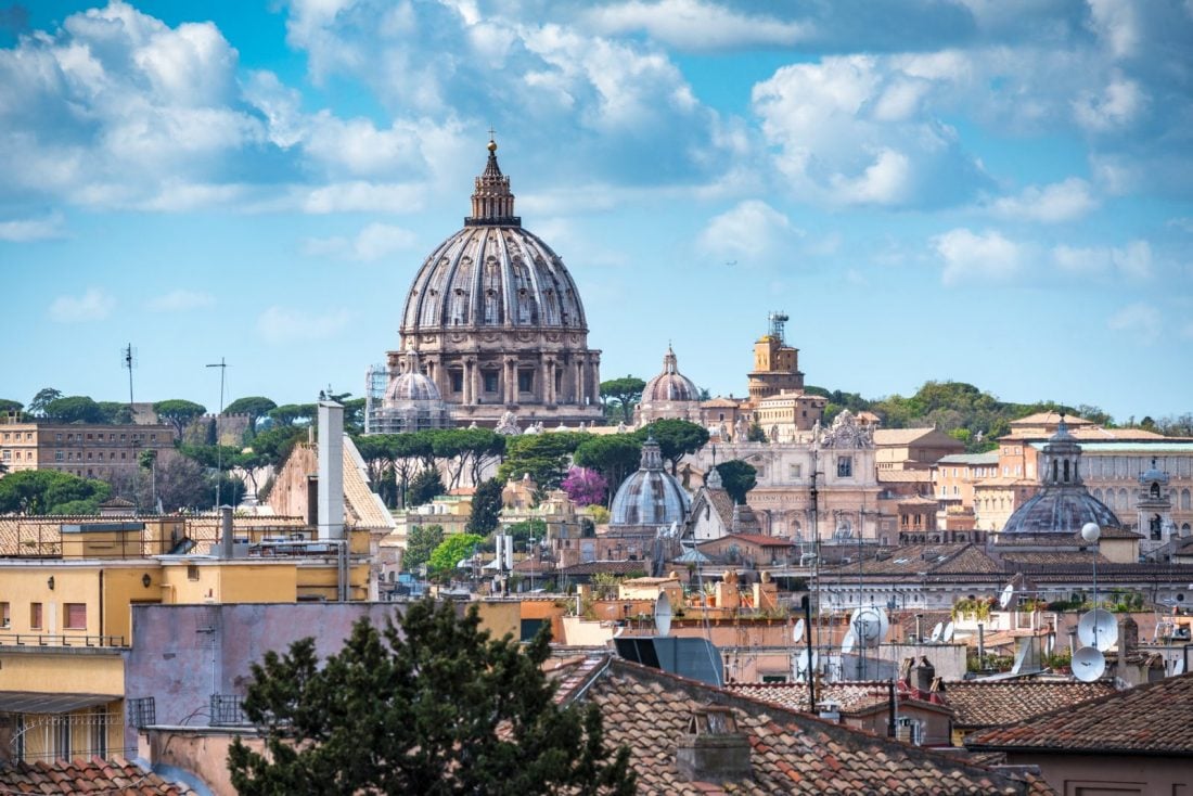 The dome of the Vatican rising above rooftops in Rome, Italy.