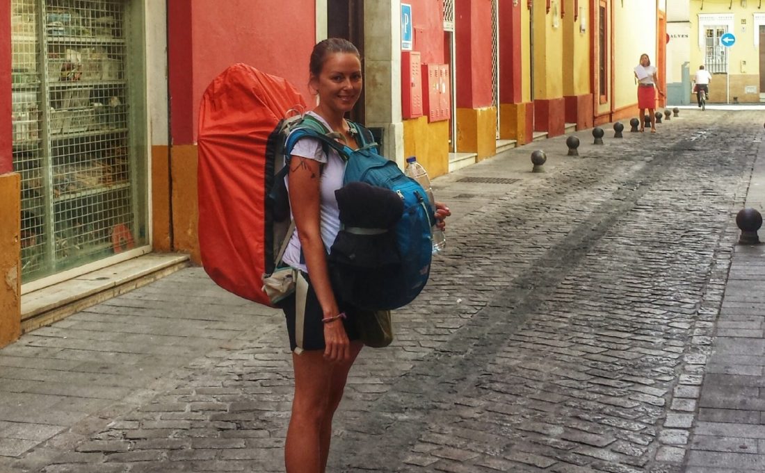 backpacking girl standing on a street in Spain with two backpacks